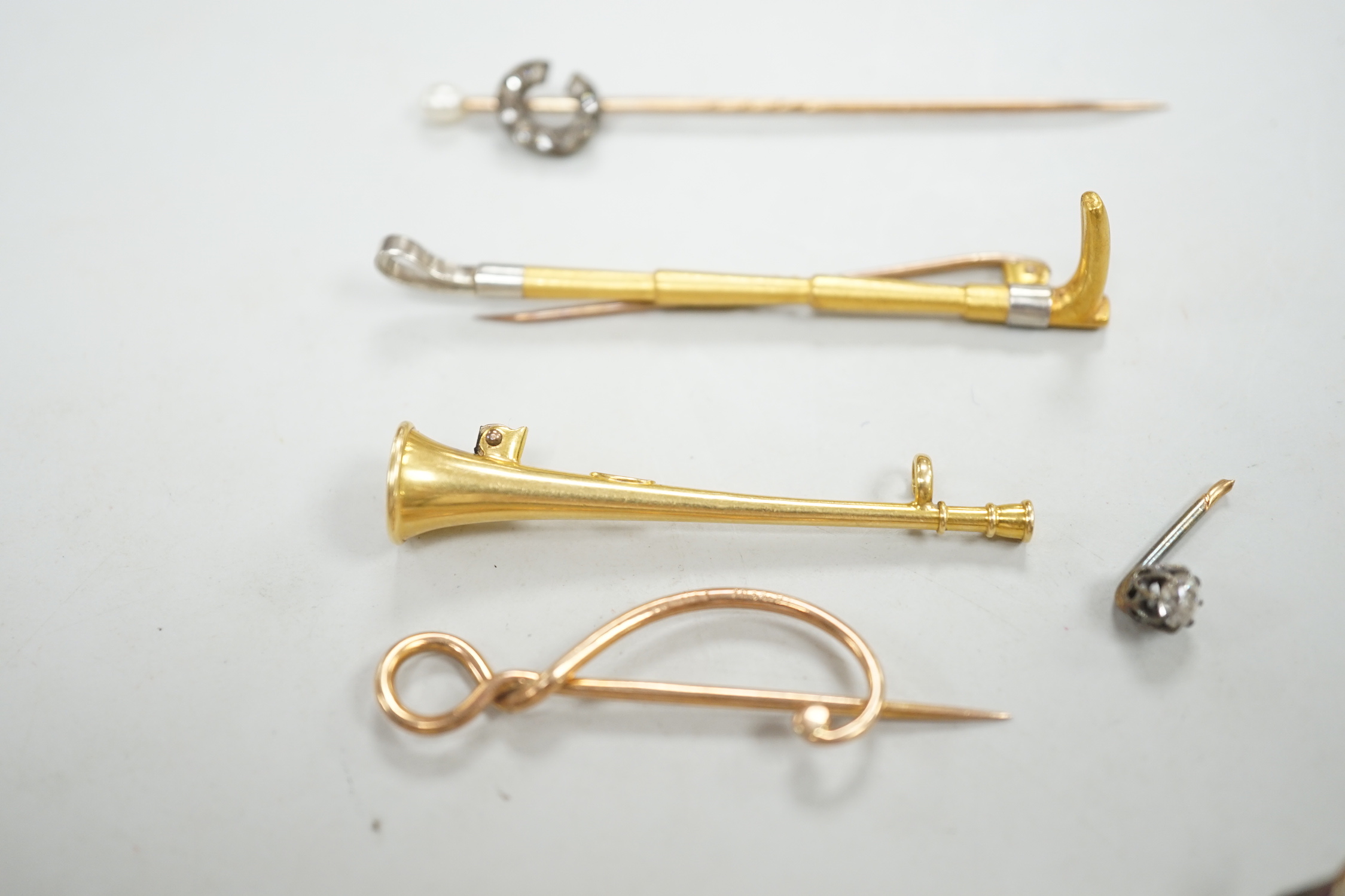 An Edwardian 15ct riding crop brooch(a.f.), 59mm, 2.8 grams, an 18ct hunting horn brooch (lacking pin) 2.1 grams, two Victorian diamond cluster set stick pins including swan in flight, a diamond set pin terminal, gross 4